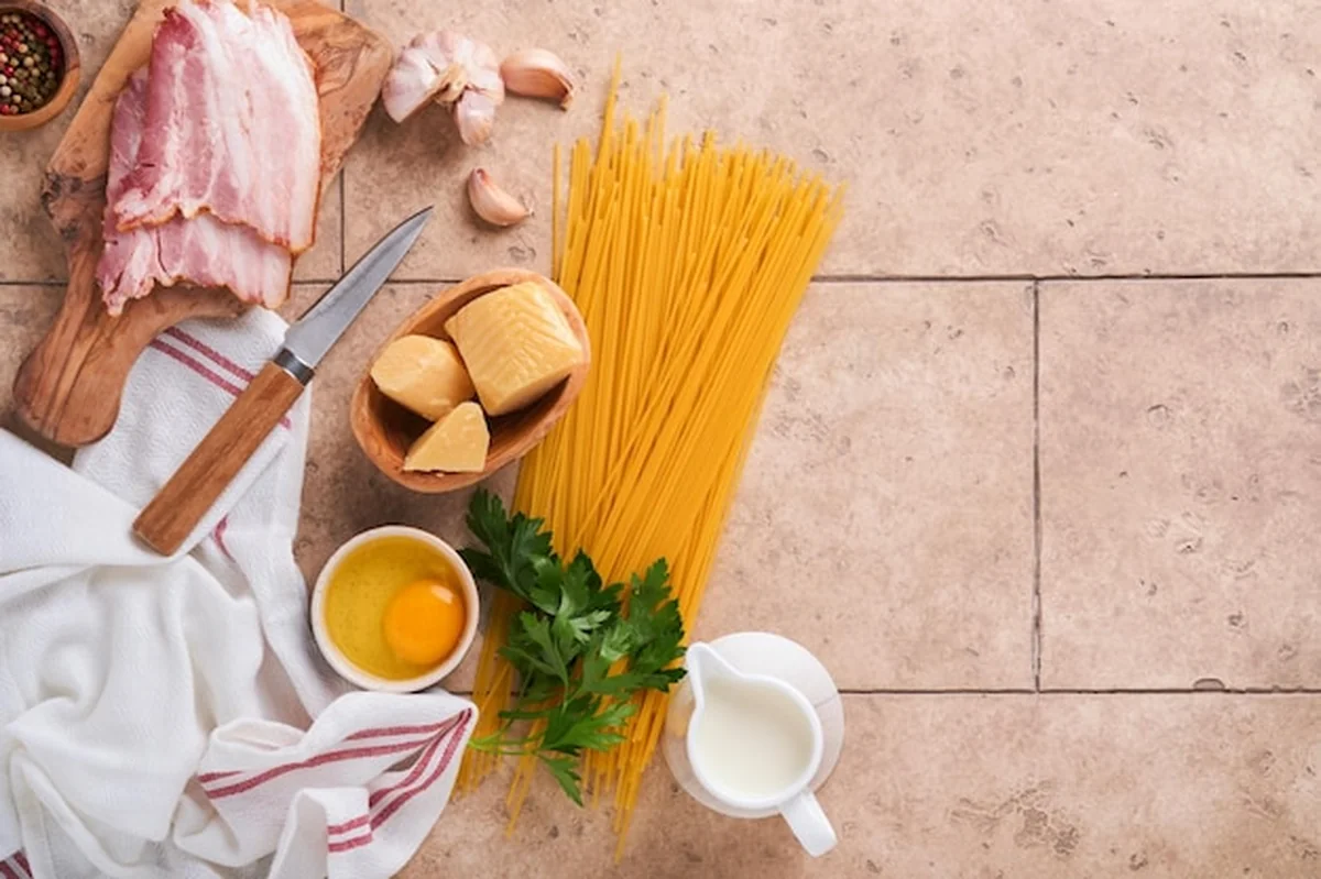 Składniki do spaghetti carbonara na beżowym tle stołu