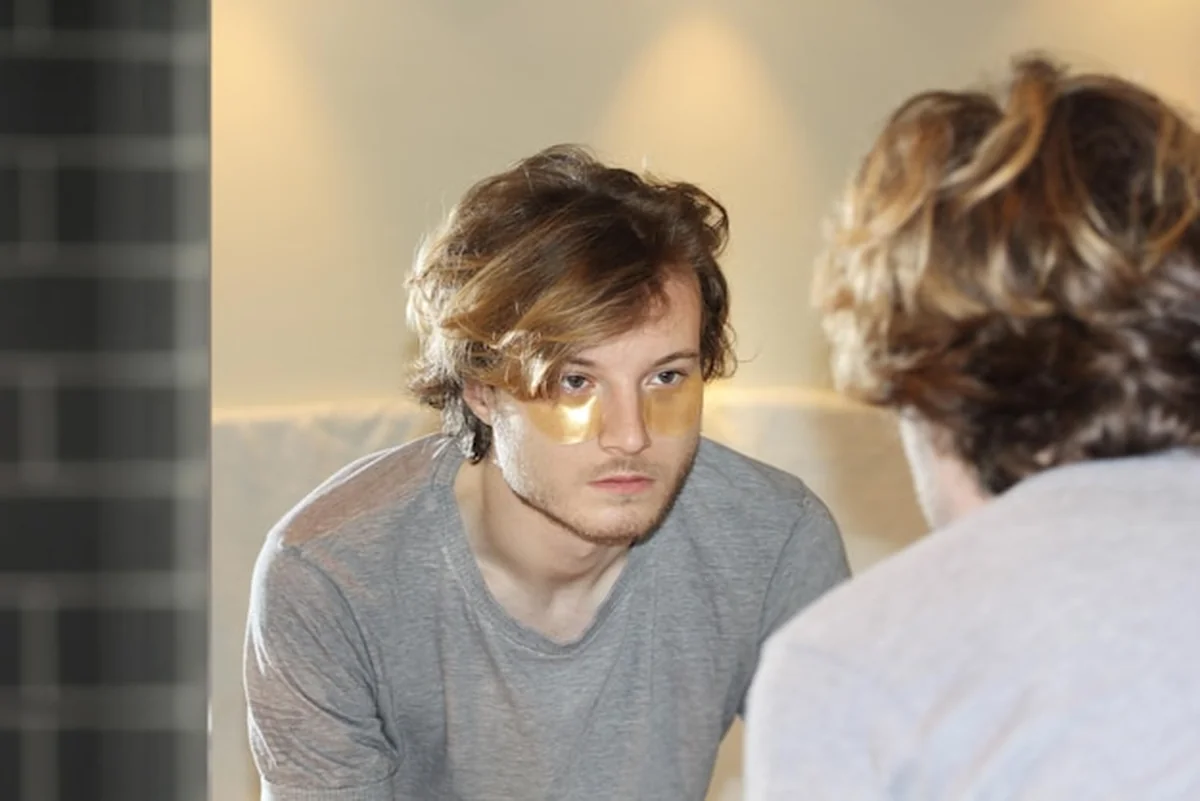 Młody mężczyzna nakłada maskę na twarz, dba o zmarszczki i ciemne kręgi