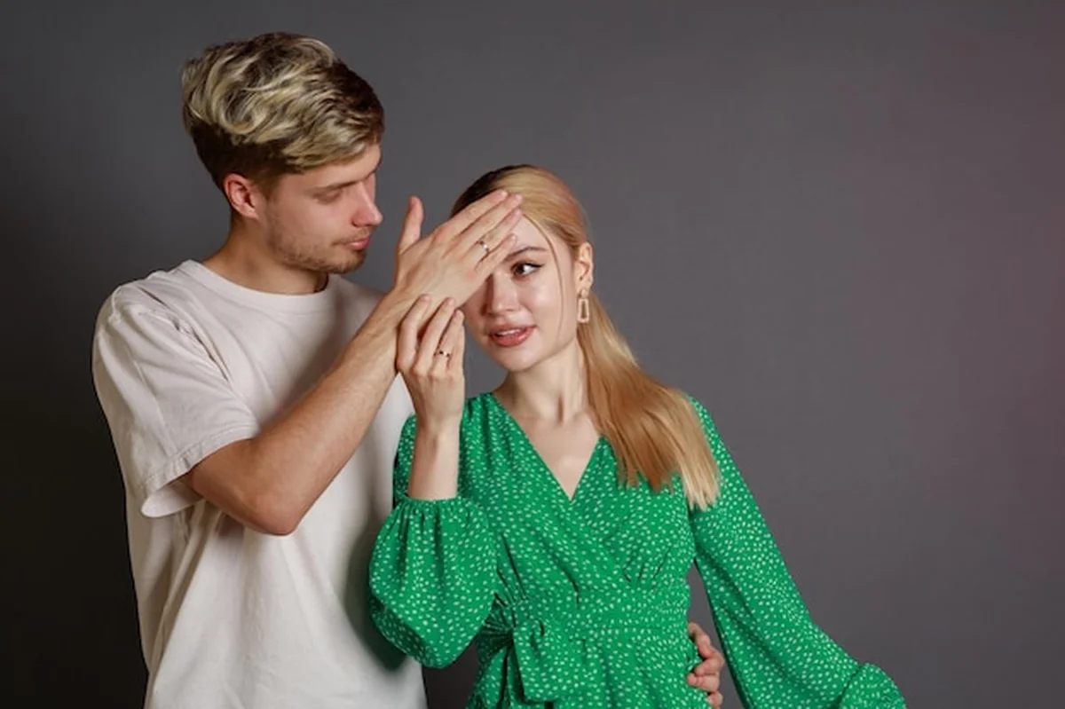 Młody mężczyzna trzymający rękę na głowie dziewczyny na szarym tle