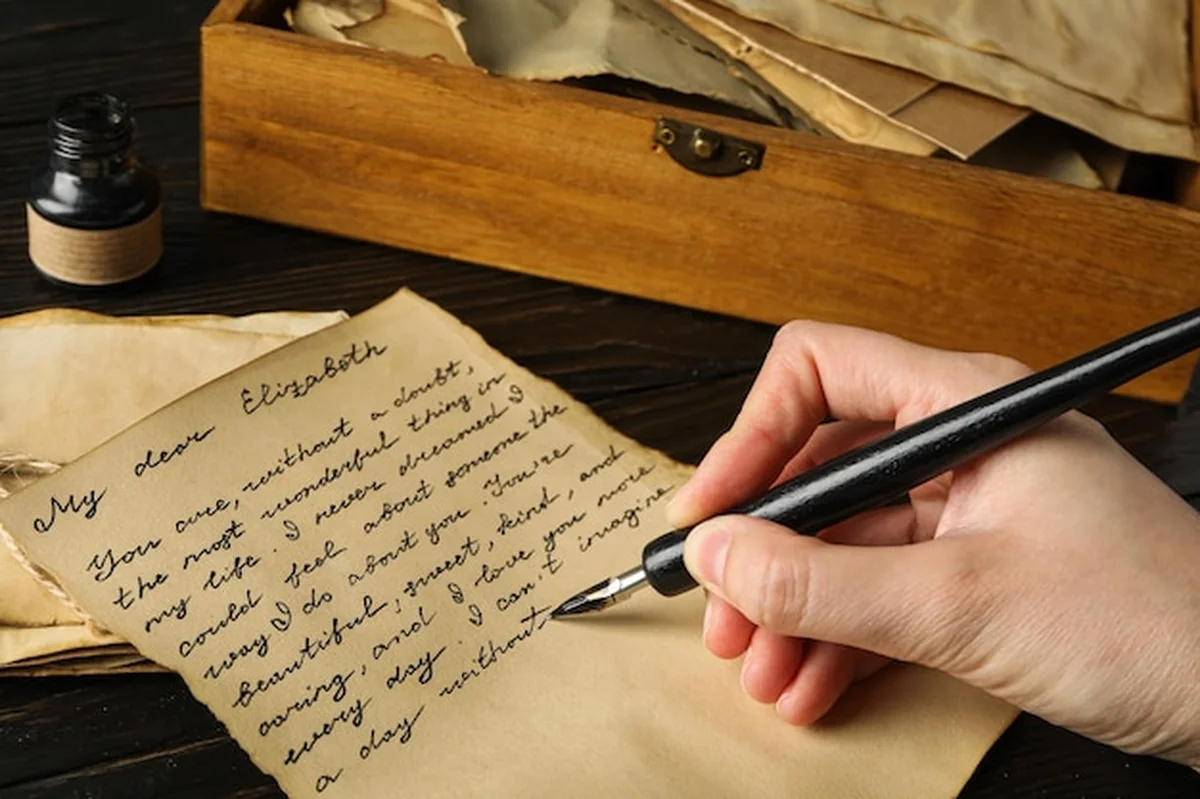 Osoba trzymająca stary list i pióro z butelką atramentu