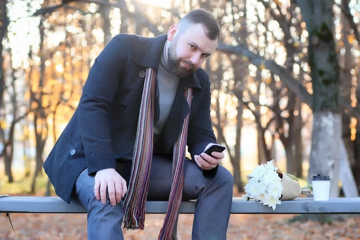 Mężczyzna czeka na ławce w parku w jesienny dzień