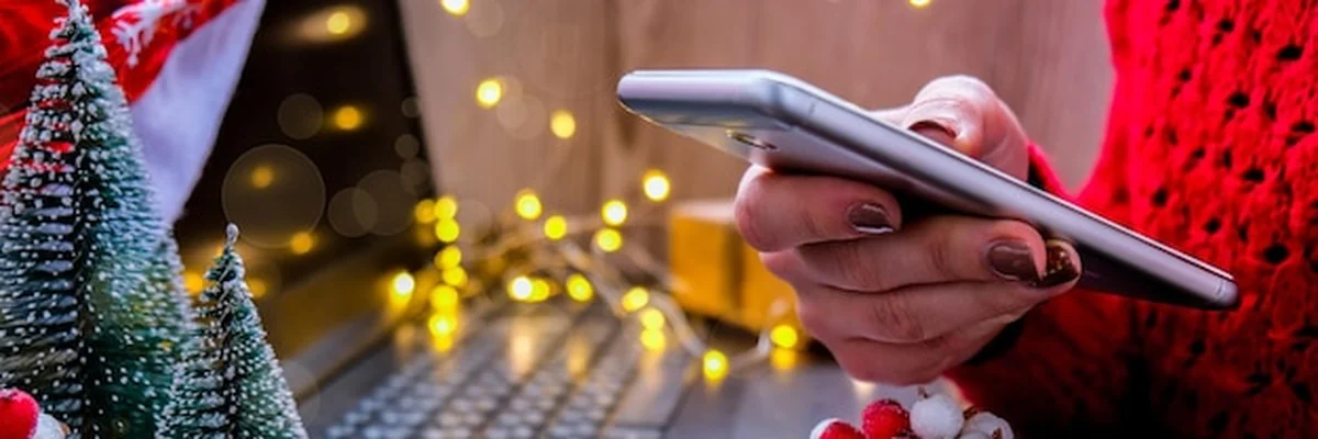 Kobieta kupuje prezenty online na Boże Narodzenie przez telefon komórkowy