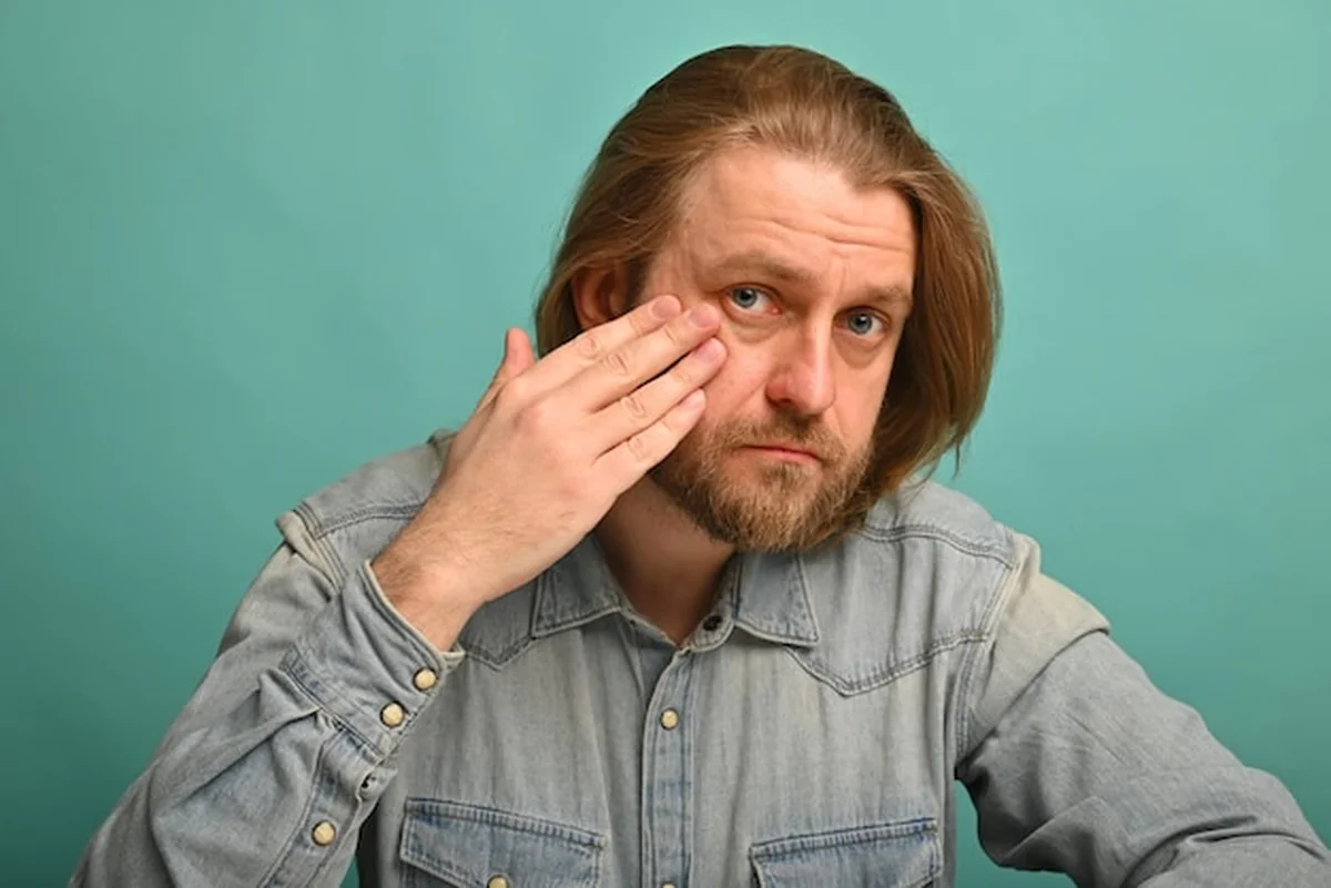 Mężczyzna patrzący na swoje zmarszczki przed lustrem