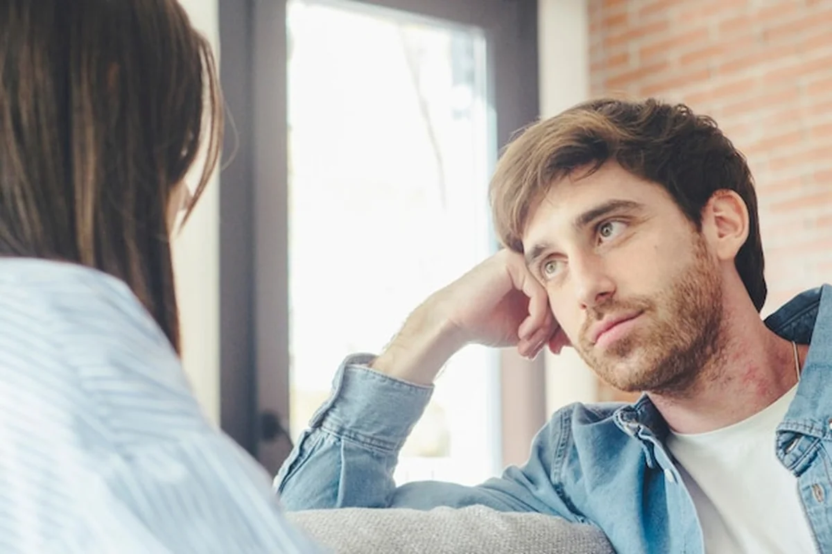 Młoda para na nowoczesnej kanapie w przytulnym mieszkaniu, rozmawiająca intymnie