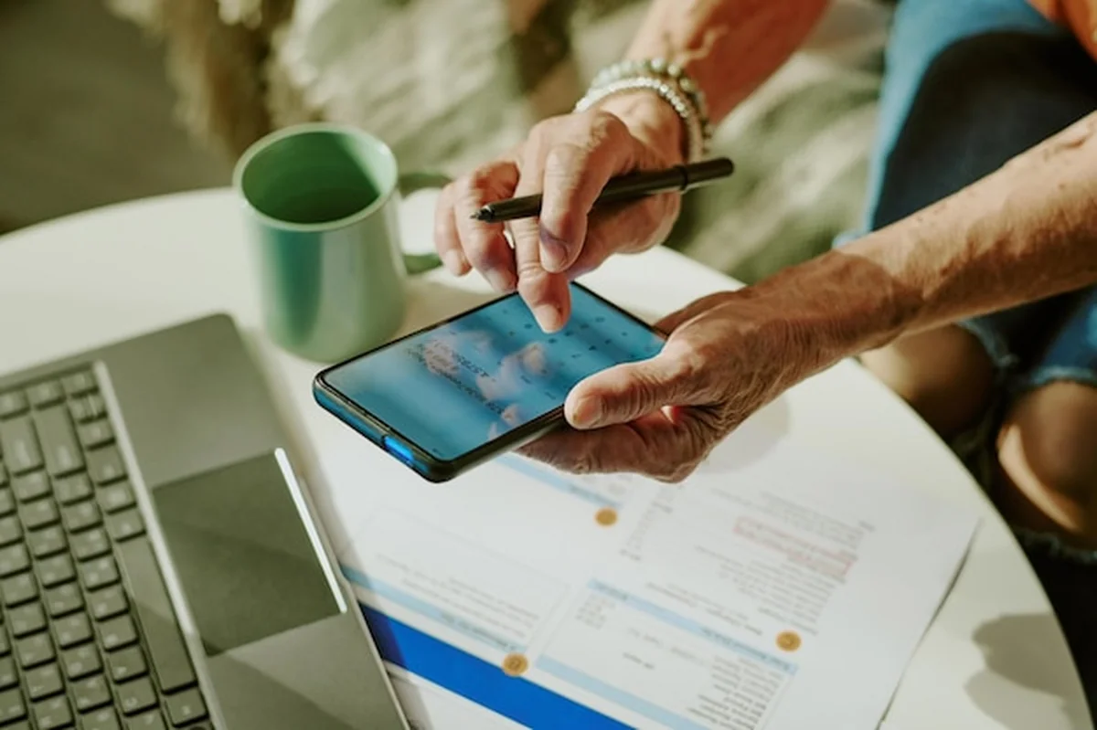 Osoba w podeszłym wieku przy biurku z tabletem i laptopem