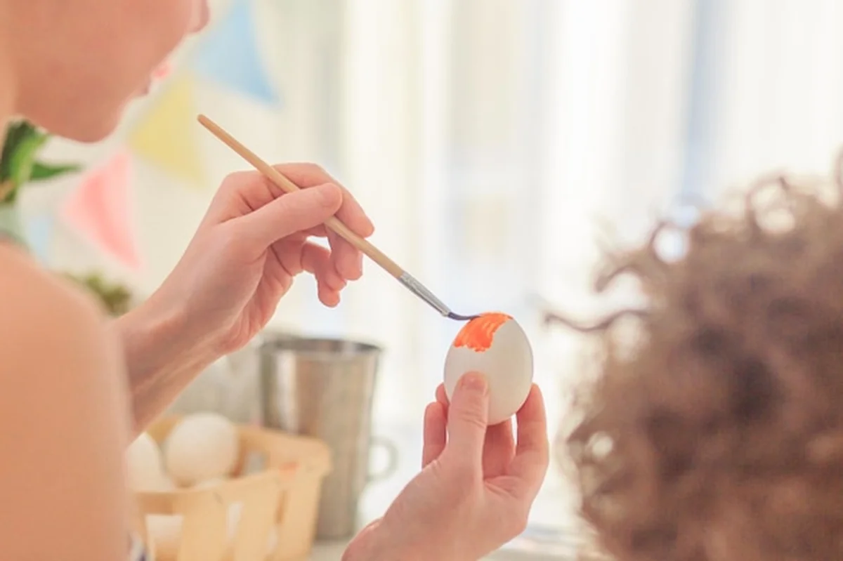 Matka i syn malują jaja wielkanocne przy stole