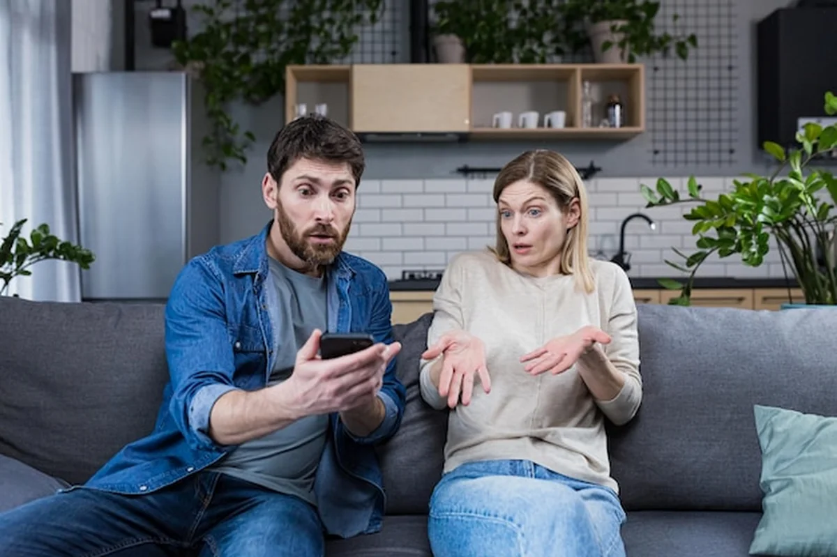 Konflikt rodzinny w domu - mężczyzna i kobieta kłócą się, pokazuje wiadomości telefoniczne