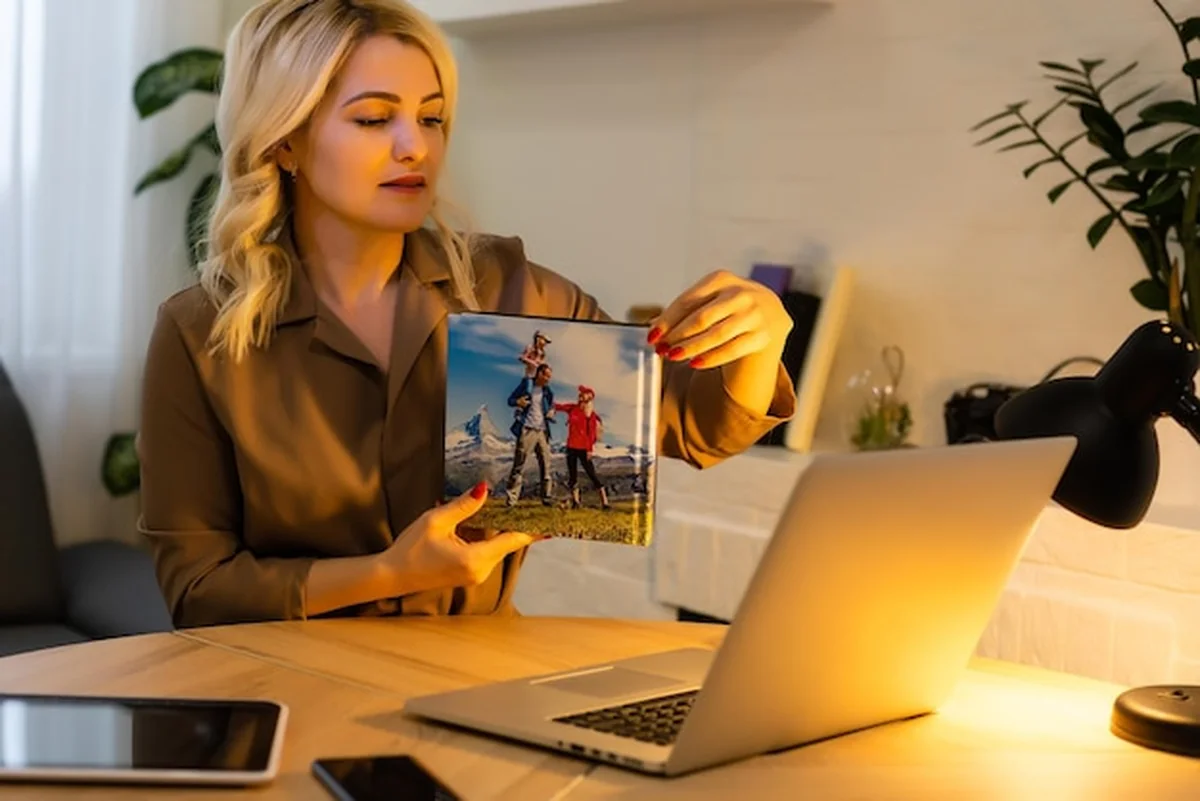 Kobieta prezentująca fotoksiążkę przy laptopie