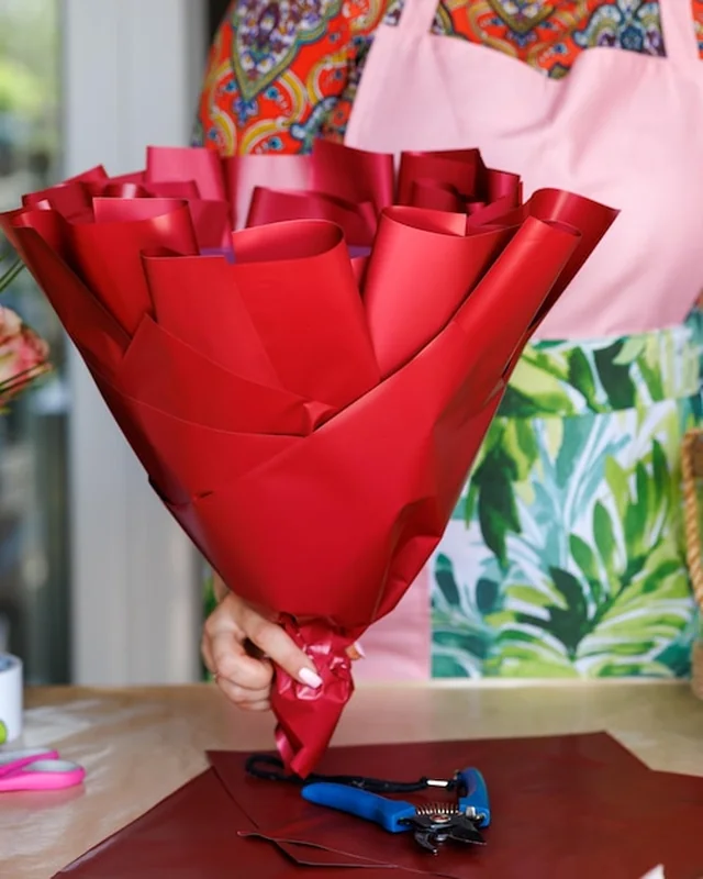 Kobieta tworzy bukiet z kwiatami i jagodami