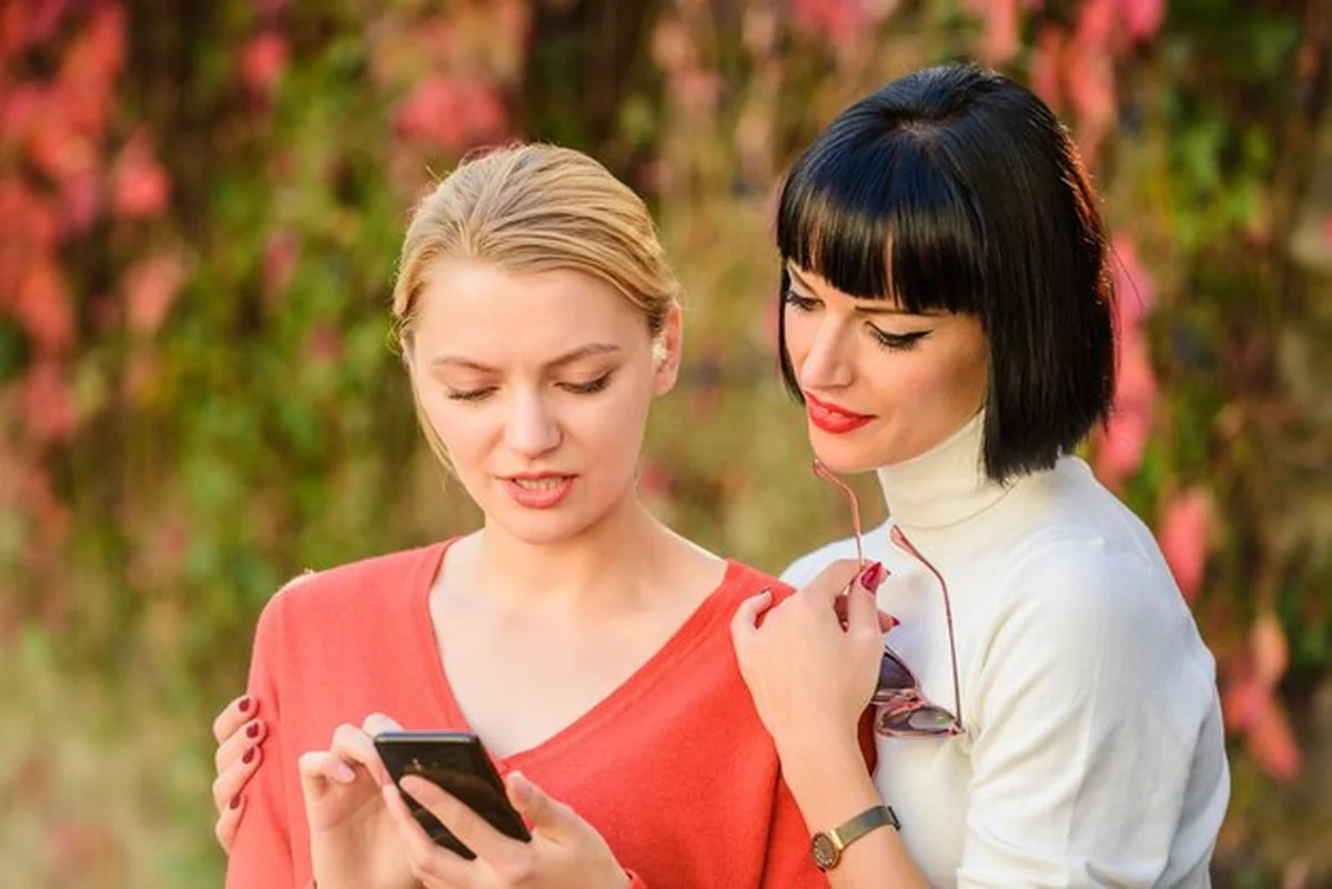 Dwie kobiety komunikujące się na zewnątrz z smartfonem