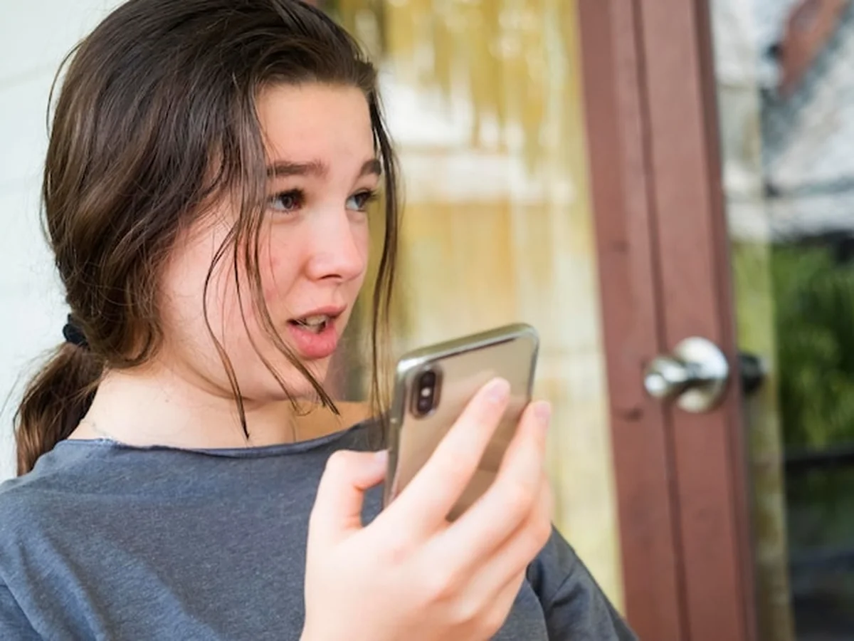 Dziewczyna używająca telefonu komórkowego na krześle przy ścianie w domu