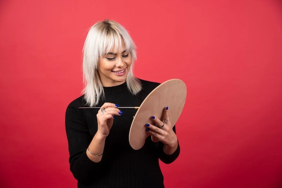 Młody artysta trzymający dzieła sztuki na czerwonej ścianie