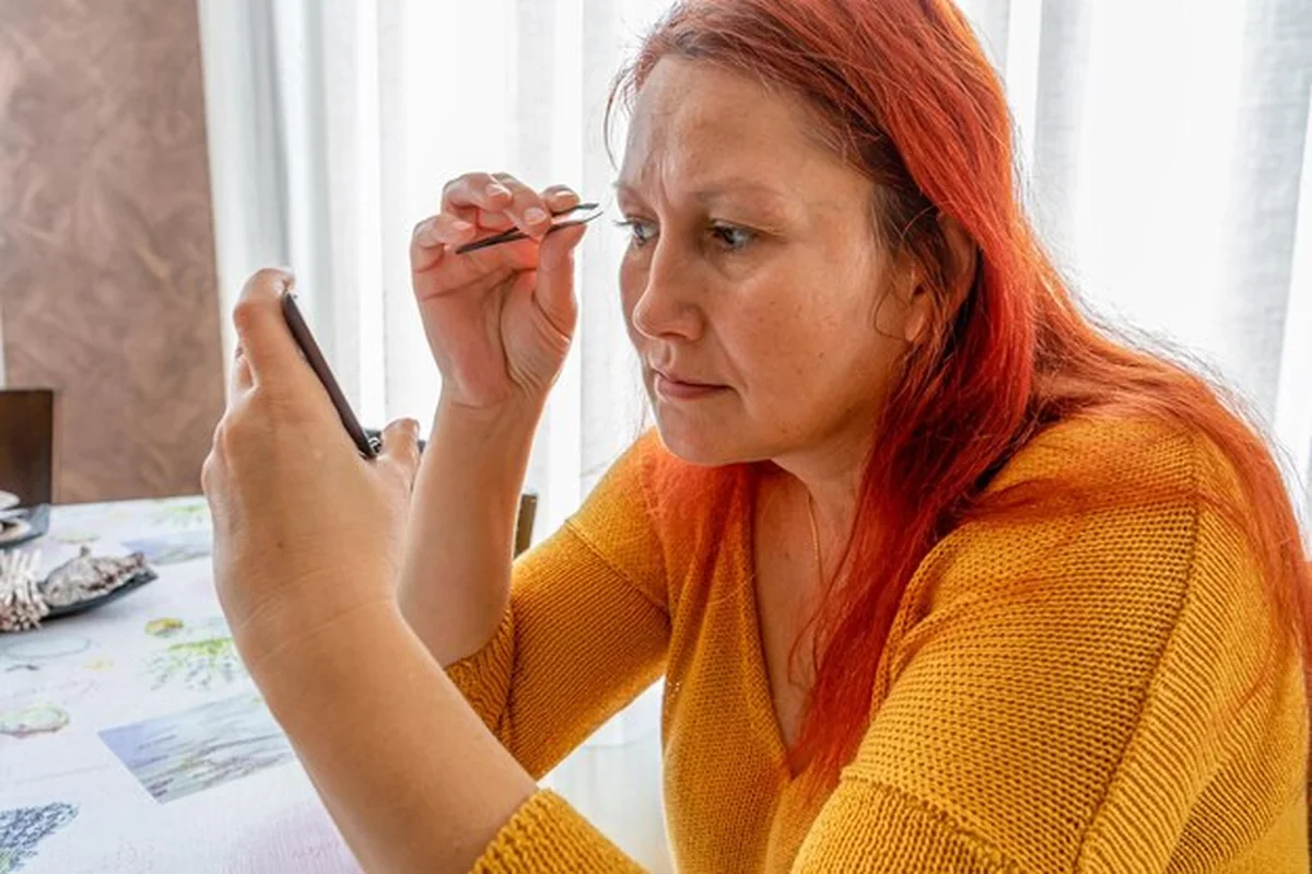 Kobieta szczypie brwi w domu