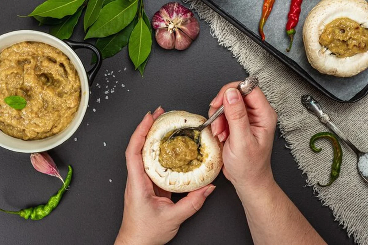 Kobiece ręce nadziewają surowe czapki grzybowe