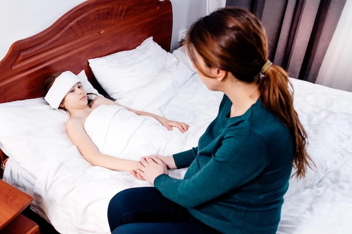 Matka z chorym dzieckiem w łóżku z gorączką