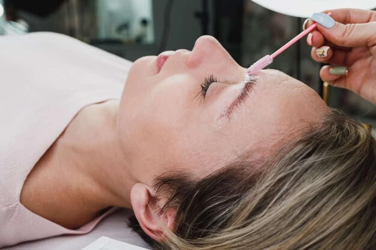 Wizażystka laminuje brwi mikro szczoteczką w salonie kosmetycznym